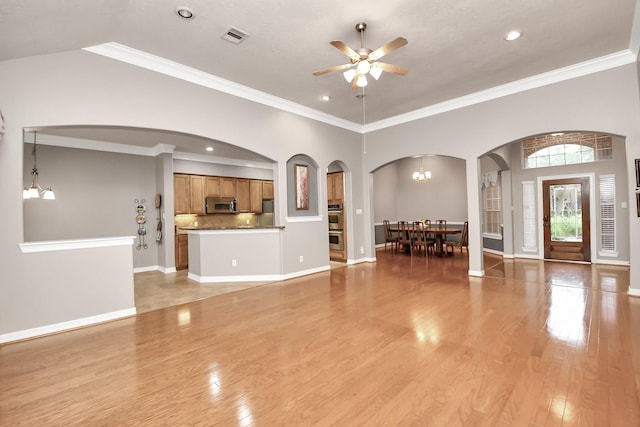 unfurnished living room with ornamental molding, ceiling fan with notable chandelier, and light wood-type flooring