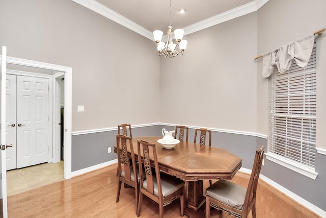 dining space with baseboards, an inviting chandelier, ornamental molding, and light wood finished floors