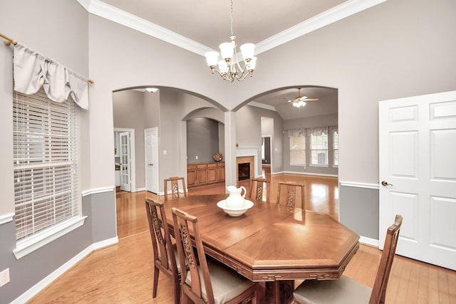 dining space with arched walkways, light wood-style floors, and a fireplace