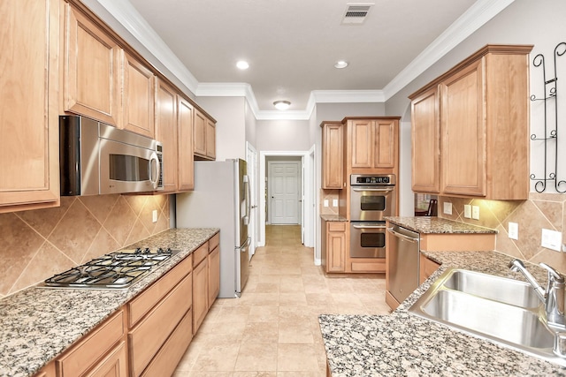 kitchen with sink, crown molding, appliances with stainless steel finishes, light stone countertops, and backsplash