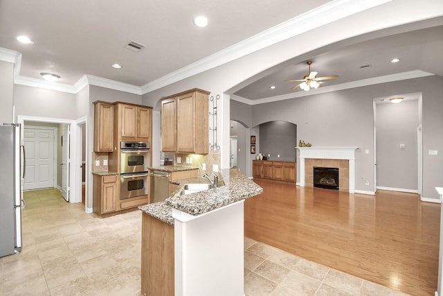 kitchen featuring sink, ceiling fan, kitchen peninsula, stainless steel appliances, and light stone countertops