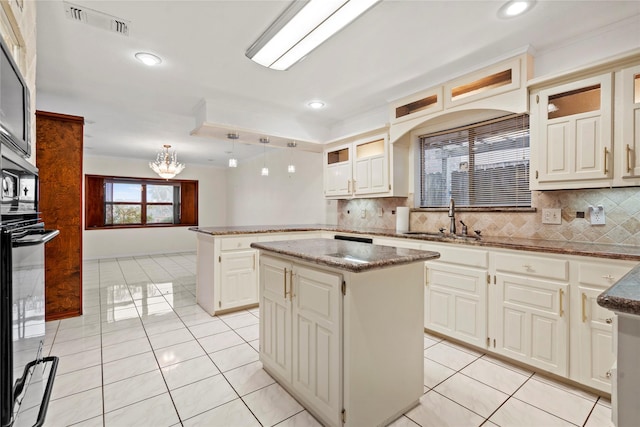 kitchen featuring light tile patterned flooring, a kitchen island, sink, and pendant lighting