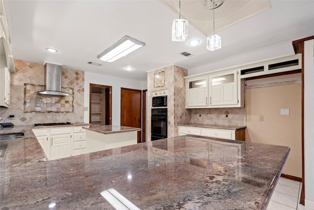 kitchen featuring dark stone countertops, black appliances, a center island, and exhaust hood