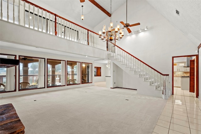 unfurnished living room featuring carpet, a towering ceiling, and ceiling fan with notable chandelier