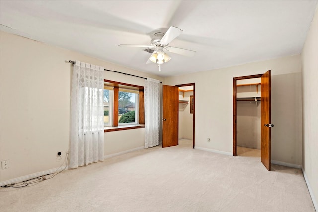 unfurnished bedroom with two closets, light colored carpet, and ceiling fan