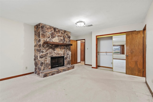 unfurnished living room featuring a stone fireplace and light colored carpet