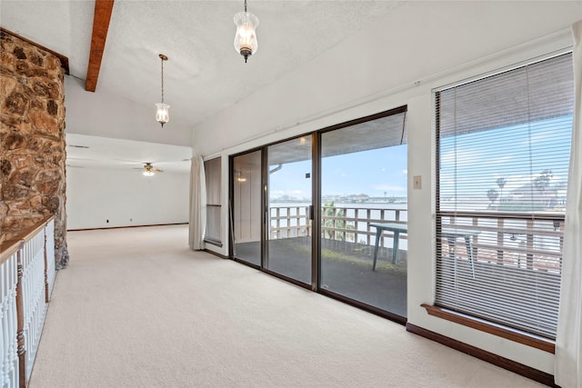 empty room featuring lofted ceiling with beams, ceiling fan, carpet floors, and a textured ceiling