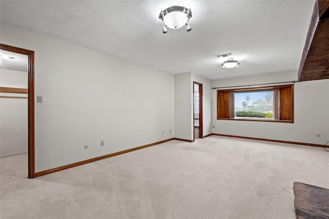 empty room with light colored carpet and a textured ceiling