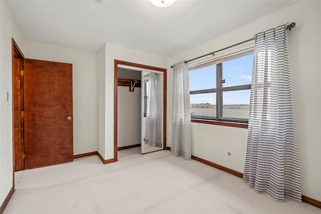 unfurnished bedroom with light colored carpet and a closet