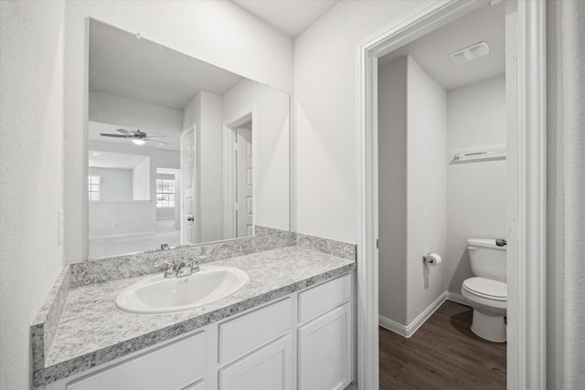 bathroom with hardwood / wood-style flooring, ceiling fan, vanity, and toilet