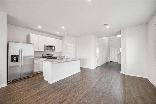 kitchen with appliances with stainless steel finishes, white cabinetry, an island with sink, dark hardwood / wood-style flooring, and light stone counters