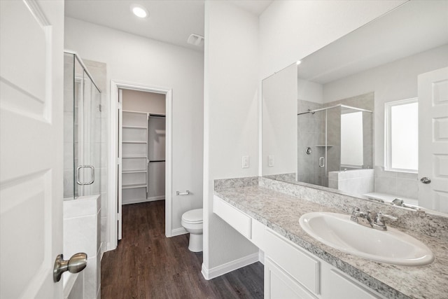 full bathroom featuring hardwood / wood-style flooring, plus walk in shower, vanity, and toilet