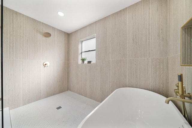 bathroom with tile walls and independent shower and bath