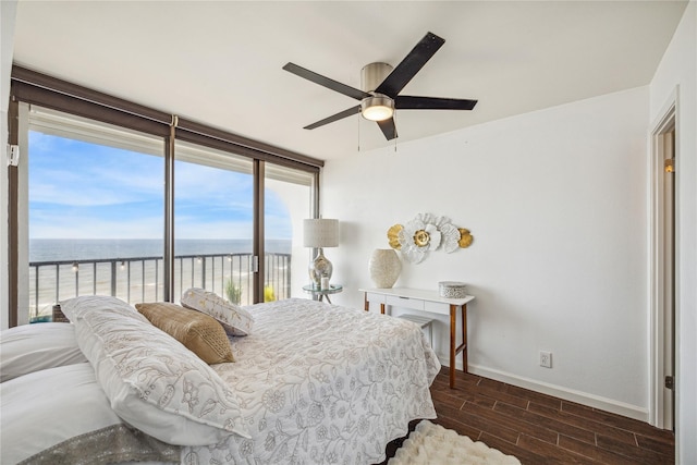 bedroom featuring a view of the beach, access to outside, ceiling fan, and a water view