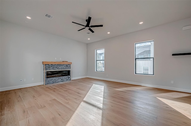 unfurnished living room with ceiling fan, a fireplace, and light hardwood / wood-style floors