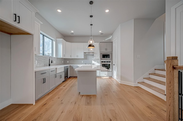 kitchen featuring white cabinetry, appliances with stainless steel finishes, a center island, and decorative light fixtures