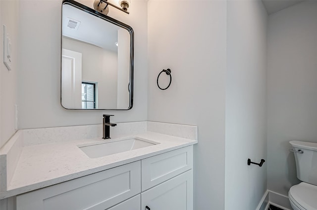 bathroom featuring toilet, vanity, and visible vents