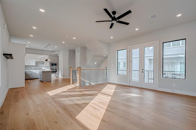 unfurnished living room with french doors, ceiling fan, and light hardwood / wood-style flooring