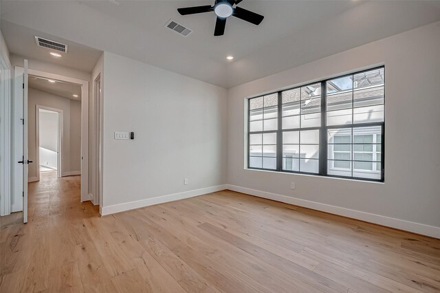 spare room featuring light wood finished floors, baseboards, and visible vents