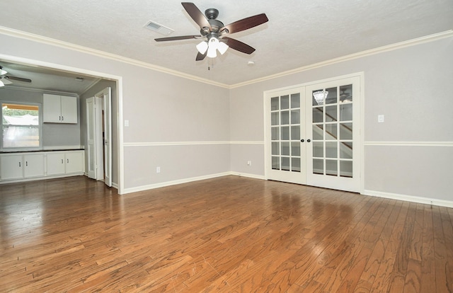 empty room featuring wood finished floors, visible vents, a ceiling fan, ornamental molding, and french doors