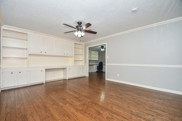 unfurnished living room featuring a textured ceiling, built in desk, dark wood-style flooring, and baseboards