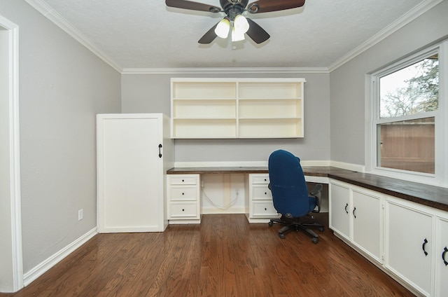 unfurnished office featuring crown molding, a ceiling fan, dark wood finished floors, and built in desk