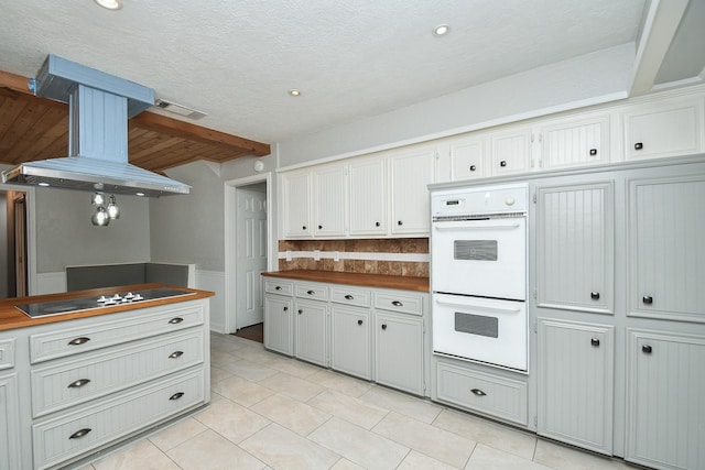 kitchen featuring visible vents, butcher block countertops, black electric stovetop, double oven, and exhaust hood