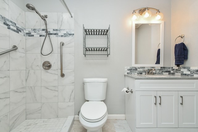 full bathroom with toilet, baseboards, a tile shower, and vanity