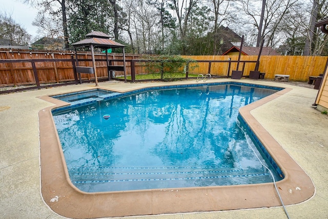 view of pool featuring a patio area, a fenced backyard, a pool with connected hot tub, and a gazebo