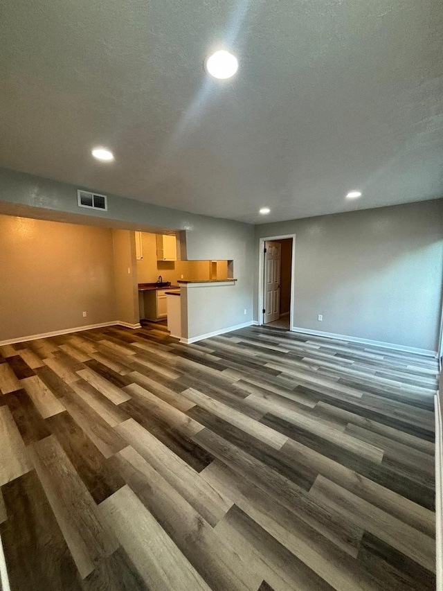 unfurnished living room featuring a textured ceiling and dark hardwood / wood-style flooring