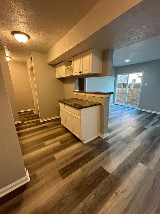 kitchen featuring dark hardwood / wood-style floors, kitchen peninsula, a textured ceiling, and white cabinets