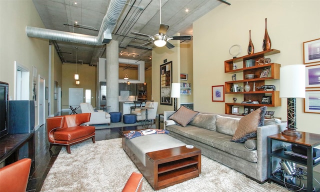 living room with ceiling fan, hardwood / wood-style floors, and a high ceiling