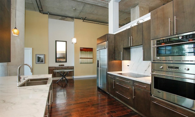 kitchen featuring pendant lighting, sink, a towering ceiling, and stainless steel appliances