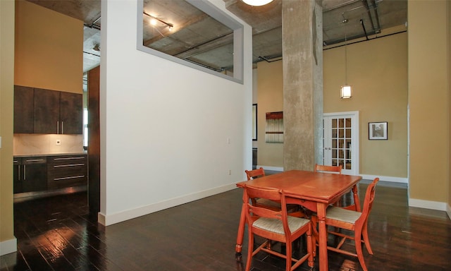 dining area featuring a high ceiling and dark wood-type flooring