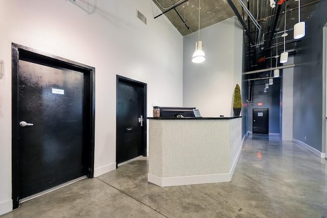 kitchen featuring concrete flooring, hanging light fixtures, and a high ceiling