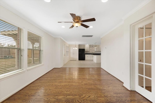 interior space featuring ornamental molding, ceiling fan with notable chandelier, and hardwood / wood-style floors