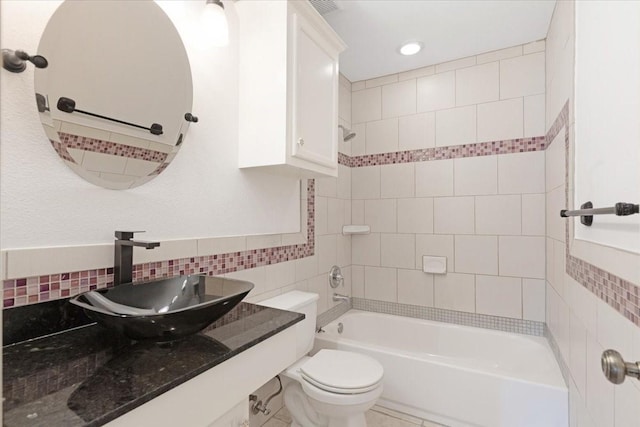 full bathroom featuring tile walls, sink, tiled shower / bath combo, and toilet