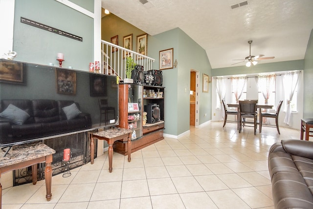 living room with a textured ceiling, vaulted ceiling, ceiling fan, and light tile patterned flooring