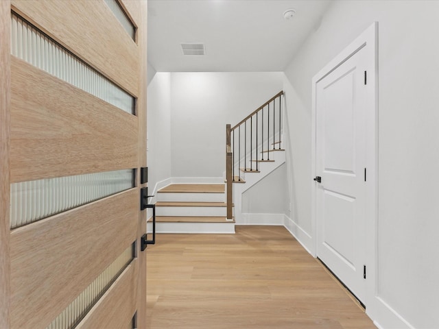 entrance foyer with stairway, wood finished floors, visible vents, and baseboards