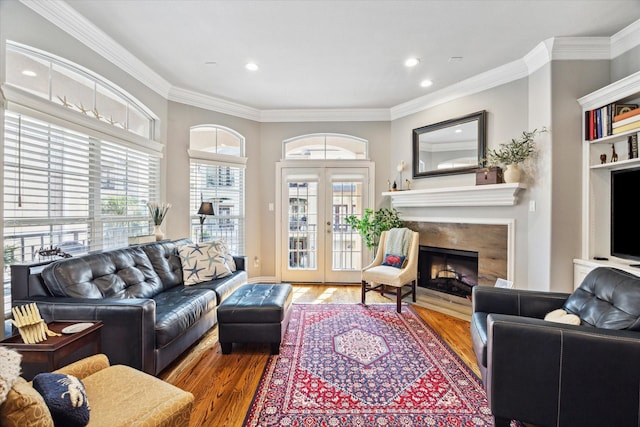 living room with crown molding, a high end fireplace, hardwood / wood-style floors, and plenty of natural light