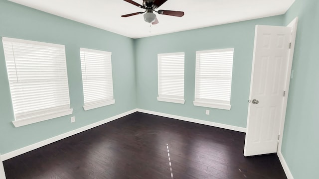 empty room with dark wood-type flooring, a wealth of natural light, and ceiling fan