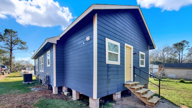 view of side of property with central AC unit and a lawn