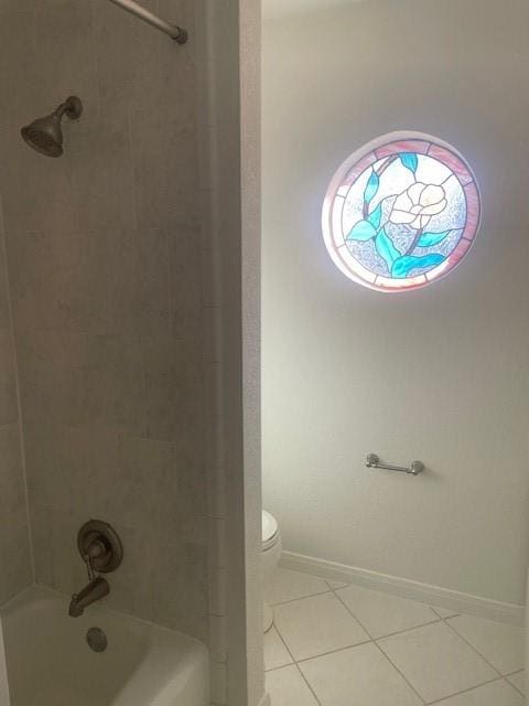 bathroom featuring tiled shower / bath, tile patterned floors, and toilet