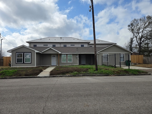 view of front of property featuring roof with shingles and fence