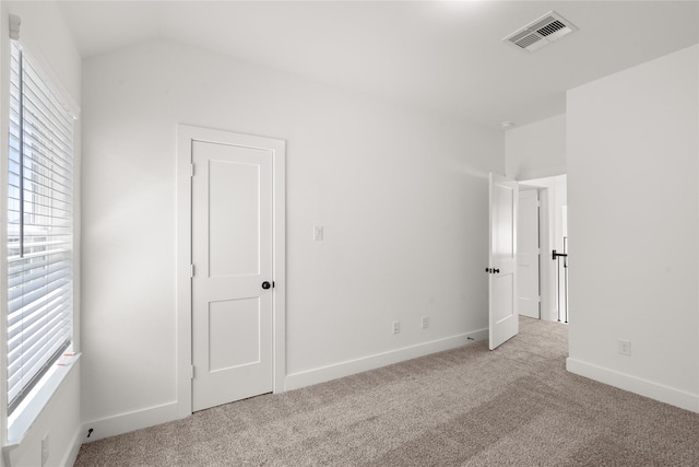 unfurnished bedroom with visible vents, baseboards, multiple windows, and carpet floors