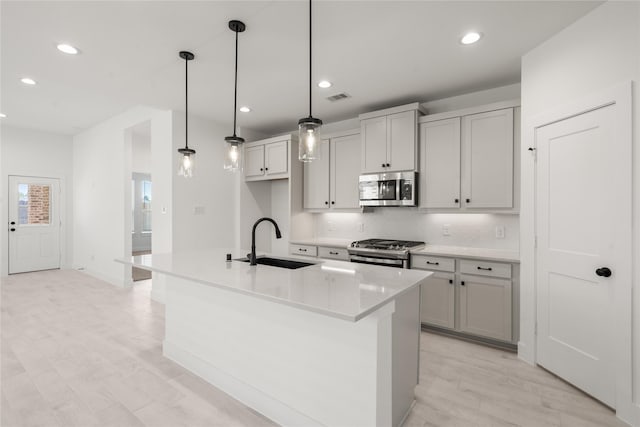 kitchen with tasteful backsplash, a sink, appliances with stainless steel finishes, recessed lighting, and light wood finished floors
