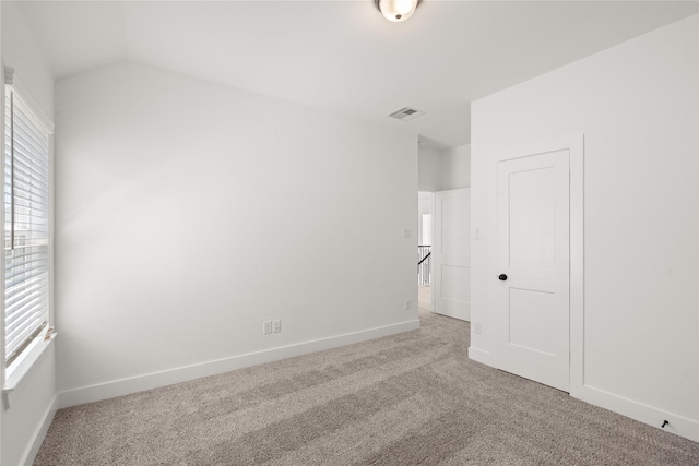 unfurnished bedroom featuring carpet, visible vents, vaulted ceiling, and baseboards