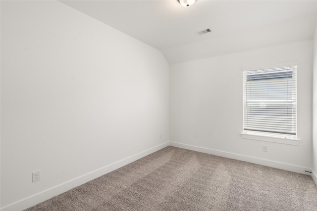 carpeted spare room with visible vents, vaulted ceiling, and baseboards