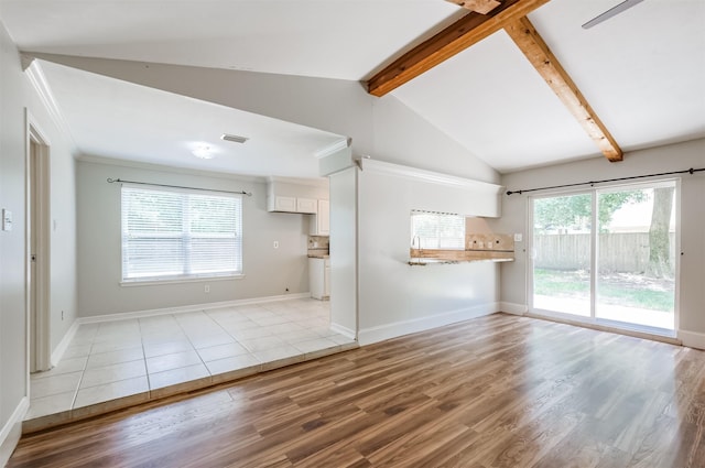 unfurnished living room featuring light hardwood / wood-style flooring and lofted ceiling with beams