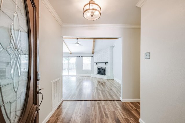 entrance foyer with wood-type flooring, ornamental molding, ceiling fan with notable chandelier, and a fireplace